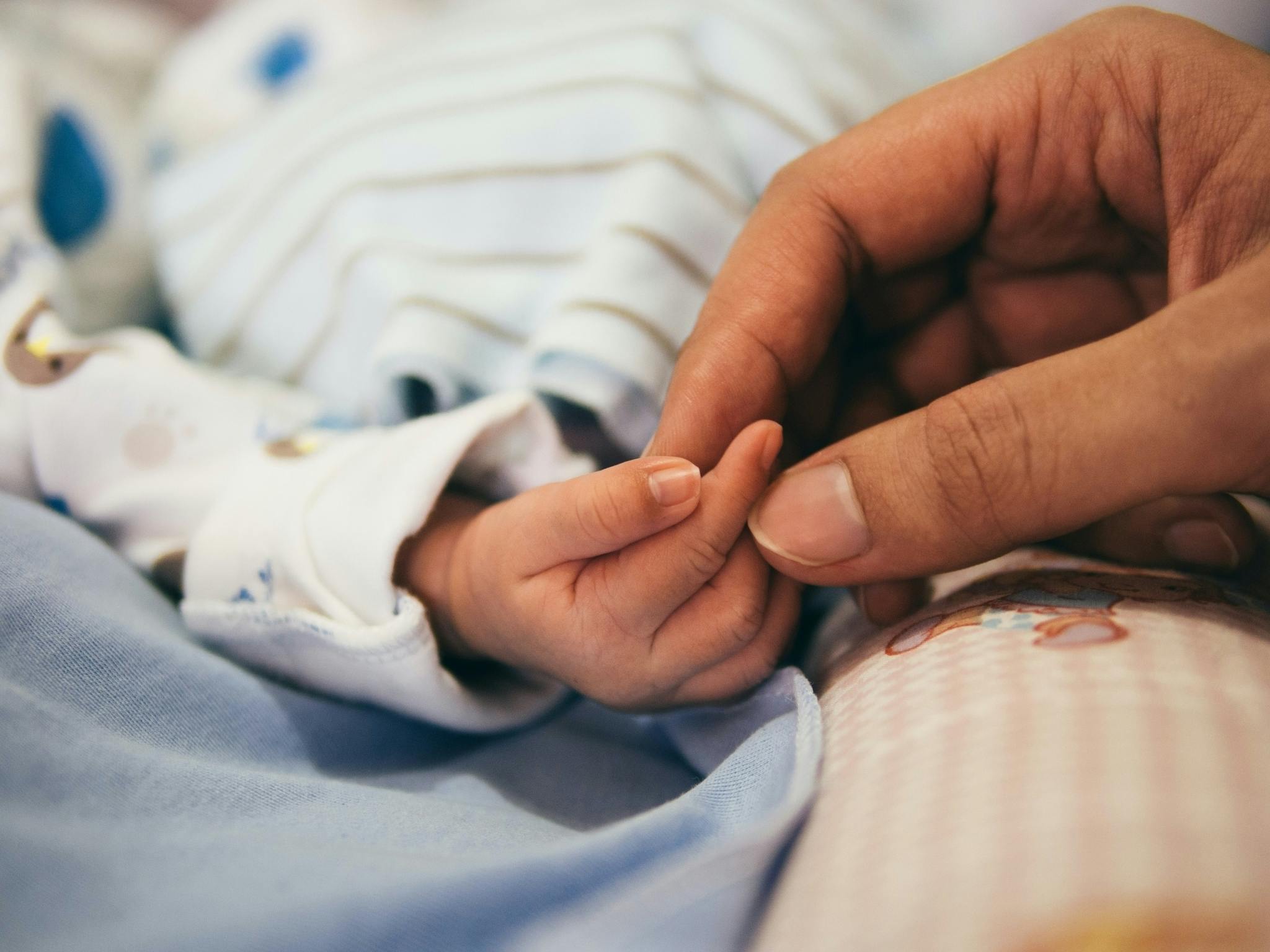 Parent holding a new born baby's hand in a Children's Hospital
